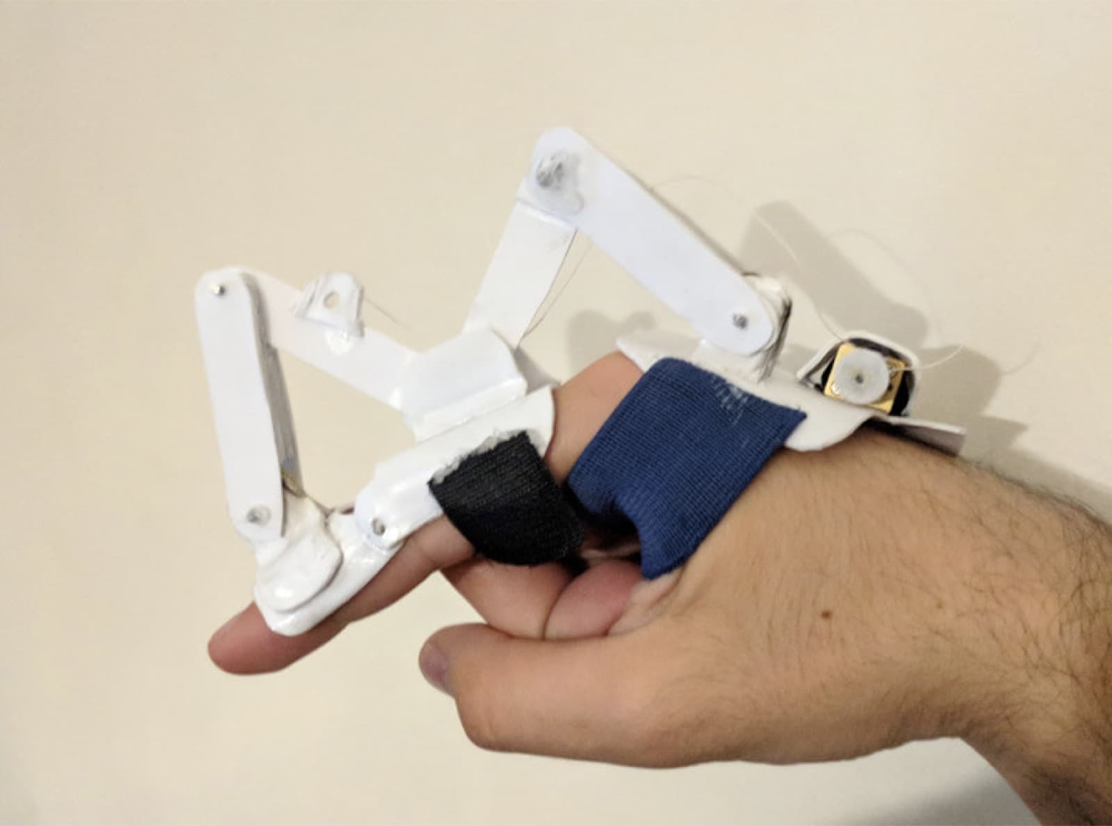 The 3D-printed exoskeleton linkage we pivoted to, strapped over two fingers